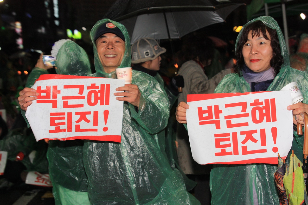 비가오는 가운데 26일 시국대회에 참가한 한 부부가 박근혜 퇴진을 외치고 있다.