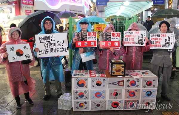 "뻔뻔한 얼굴과 말, 보기도 듣기도 싫다" 부산광역시 서면에서 13만명의 시민들이 모인 가운데 열린 시국대회에서 비옷을 입은 시민들이 다양한 내용이 적힌 손피켓을 들고 있다.