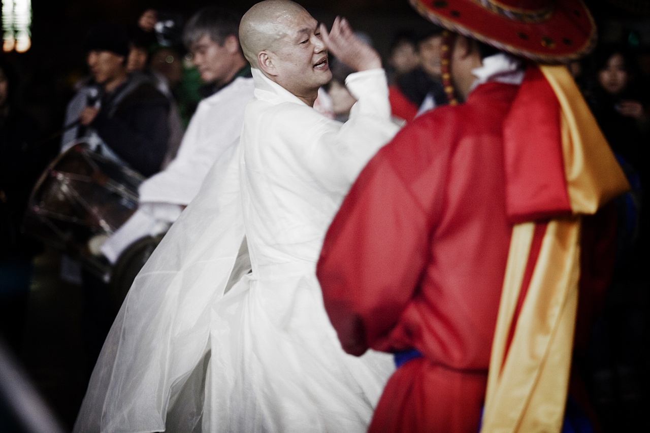 촛불집회 현장에서 승려로 보이는 한 집회 참가자가 사물놀이를 하는 무리에 섞여 춤을 추고 있다.