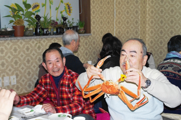  큼지막한 대게를 든 관광객이 환히 웃고 있다.