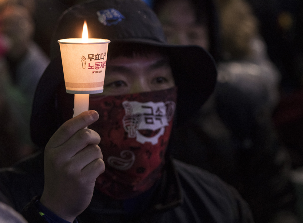  30일 충남 천안시 동남구 종합터미널에서 열린 총파업-시민불복종 집회에서 한 금속노조 조합원이 촛불을 들고 집회에 참여하고 있다. 