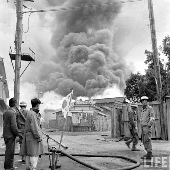 1948년 10월 23일, 여순사건을 진압하기 위해 진압군이 투입됐다. 해군 LST함이 여수앞바다 선상에서 시내를 향해 무자비한 박격포 공격을 하자 여수시내가 불타고 있는 모습. 그 모습을 군인들이 지켜보고 있다.