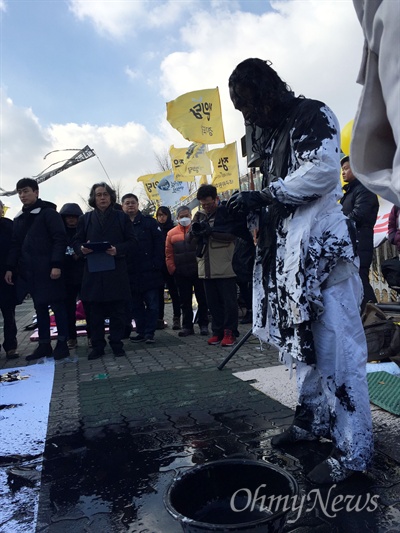  배희권 화백이 9일 낮 박근혜 대통령 탄핵안 의결을 앞둔 여의도 국회 정문 앞에서 자신의 머리카락을 붓삼아 '대통령 탄핵하라'를 쓴 뒤 남은 먹물을 자신의 몸에 뒤집어 쓰고 있다.