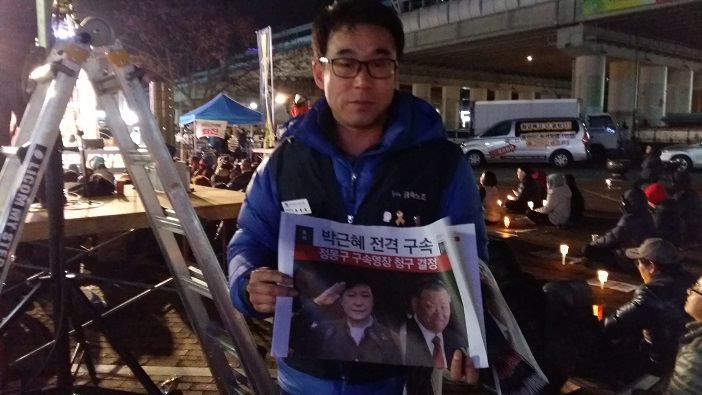 한 시민이 '박근혜 전격 구속'을 다룬 가상 신문을 나눠주고 있다. 
