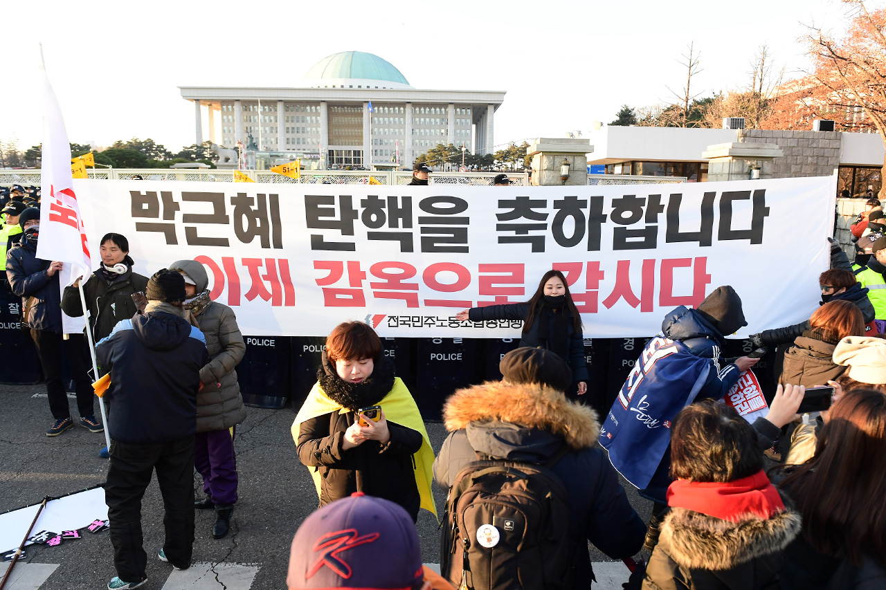 9일 오후 국회 본회의에서 박근혜 대통령에 대한 탄핵안이 통과되자 여의도 국회앞 거리에 모여있던 국민들이 '탄핵' 기념사진을 찍고 있다.