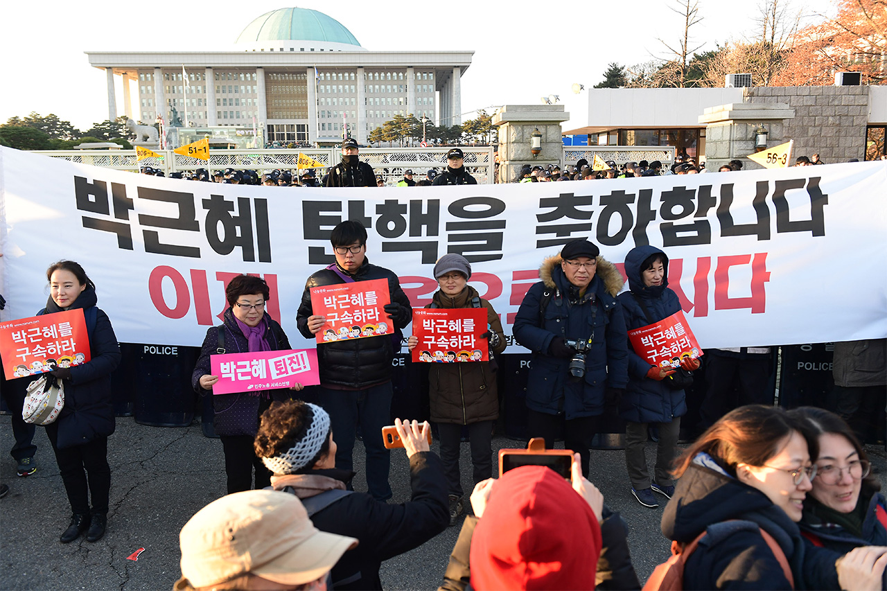 9일 오후 국회 본회의에서 박근혜 대통령에 대한 탄핵안이 통과되자 여의도 국회앞 거리에 모여있던 국민들이 '박근혜 대통령 탄핵을 축하합니다'라는 문구가 쓰여진 현수막앞에서 기념사진을 찍고 있다.