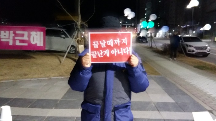 내포 촛불시민이 '끝날때 까지는 끝난게 아니다'라고 적힌 피켓을 들고 있다. 