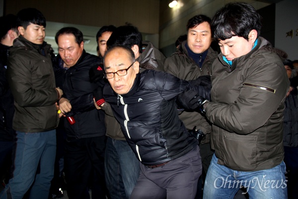 경찰이 2016년 12월 14일 오전 국립3.15민주묘지 기념관에 걸려 있는 박근혜 대통령 사진을 훼손한 혐의로 김영만 박근혜퇴진 경남운동본부 상임의장을 현행범으로 체포해 연행하고 있다.