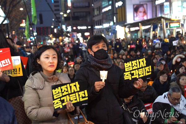17일 오후 대구 중앙로에서 열린 박근혜 퇴진 시국대회에 참가한 시민이 '범죄자 즉각 퇴진'이라고 쓴 손피켓과 촛불을 들고 앉아 있다.