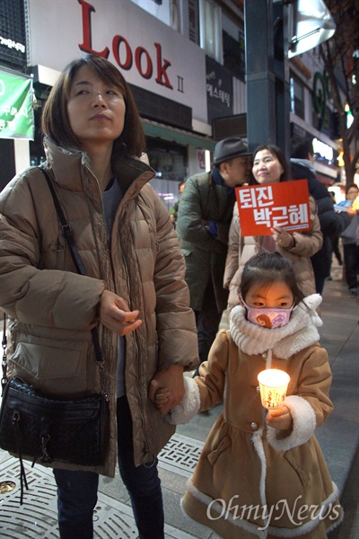 17일 오후 대구 중앙로에서 열린 박근혜 퇴진 시국대회에 참가한 한 시민이 촛불을 든 어린 여자아이의 손을 꼭 잡고 서 있다.