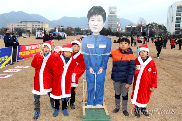 24일 오후 창원광장에서 열린 '박근혜퇴진 9차 경남시국대회'에서 어린이들이 산타 복장을 하고 박근혜 대통령의 구속 장면 모형 앞에서 사진을 찍었다.