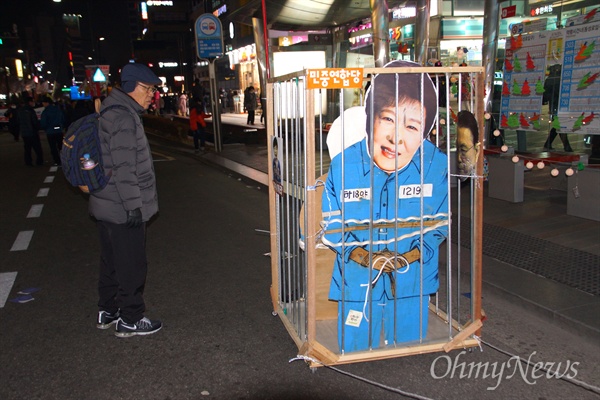24일 옿 대구에서 열린 박근혜 퇴진 시국대회에서 박근혜 대통령을 구속하는 모양을 재현하는 감옥 퍼포먼스를 벌이자 지나가던 시민이 지켜보고 있다.