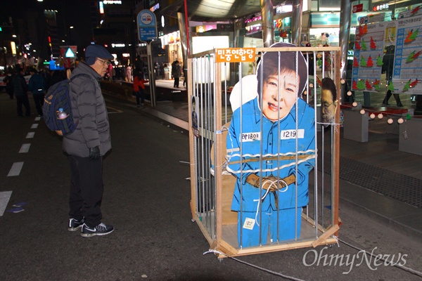  24일 옿 대구에서 열린 박근혜 퇴진 시국대회에서 박근혜 대통령을 구속하는 모양을 재현하는 감옥 퍼포먼스를 벌이자 지나가던 시민이 지켜보고 있다.