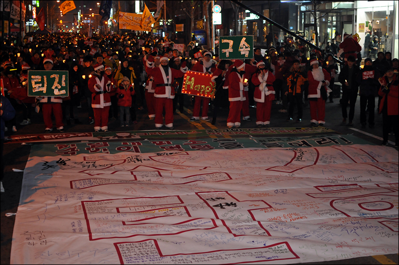 촛불집회 참가자들은 ‘조기탄핵’이라고 쓰여 진 대형현수막에 헌법재판소에 바라는 글귀를 적은 후 들고서 거리행진에 나서기도 했다.