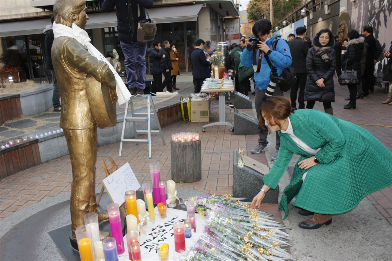 김광석 기일을 찾아 국화꽃을 전달하는 한 시민. 1월 6일 김광석의 기일 21주기가 돌아왔다. 이를 기억하는 시민들은 이곳으로 와 그의 주검을 슬퍼하며 국화꽃을 그의 동상 앞에 놓았다.