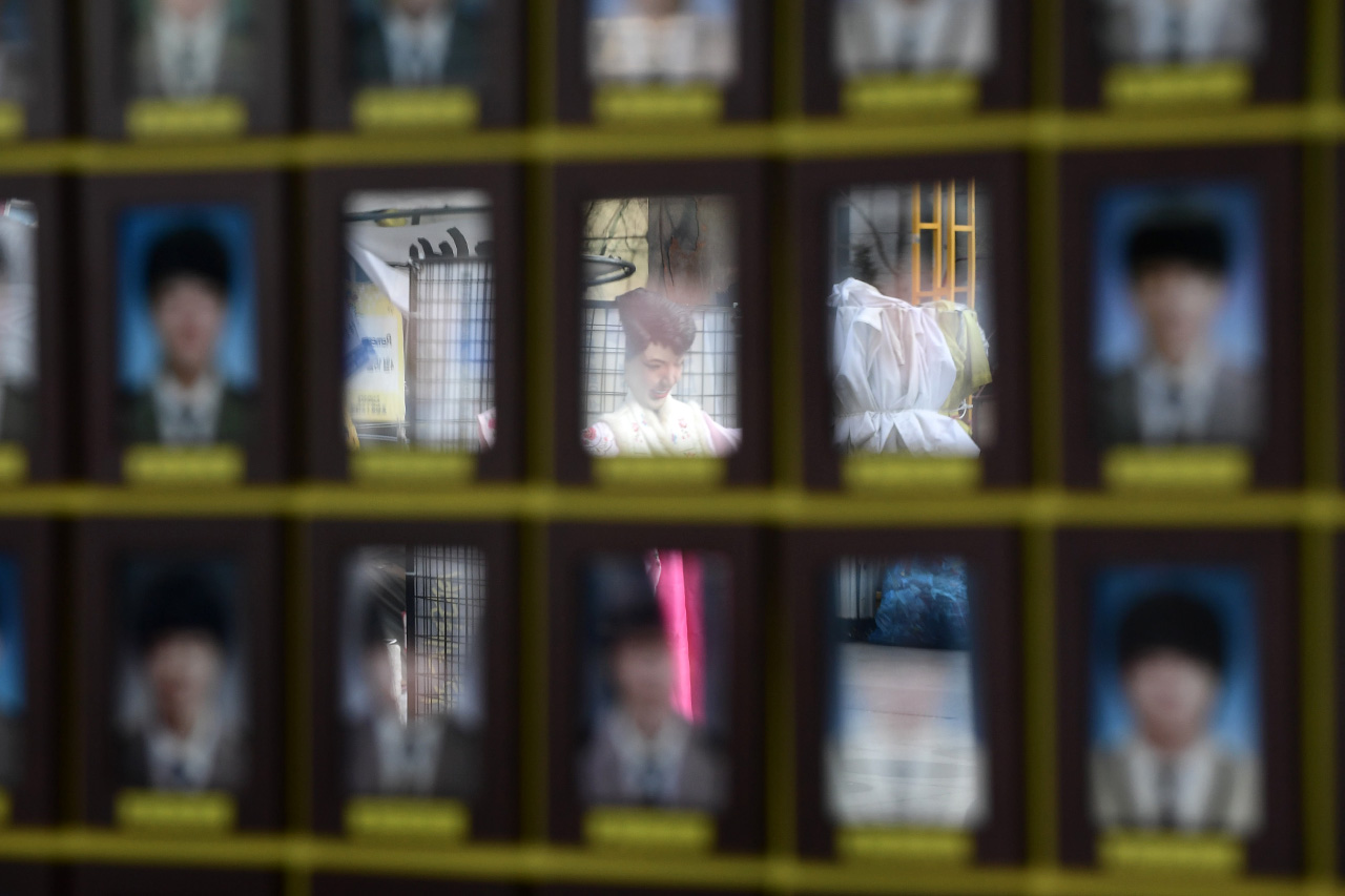 세월호 참사 1000일째를 맞이한 9일 오후 서울 종로구 광화문광장에 마련되어 있는 '세월호 참사 희생자 및 미수습자 광화문 분향소'에 놓여져 있는 희생자들의 영정사진 위로 박근혜 대통령의 모형이 비춰지고 있다.