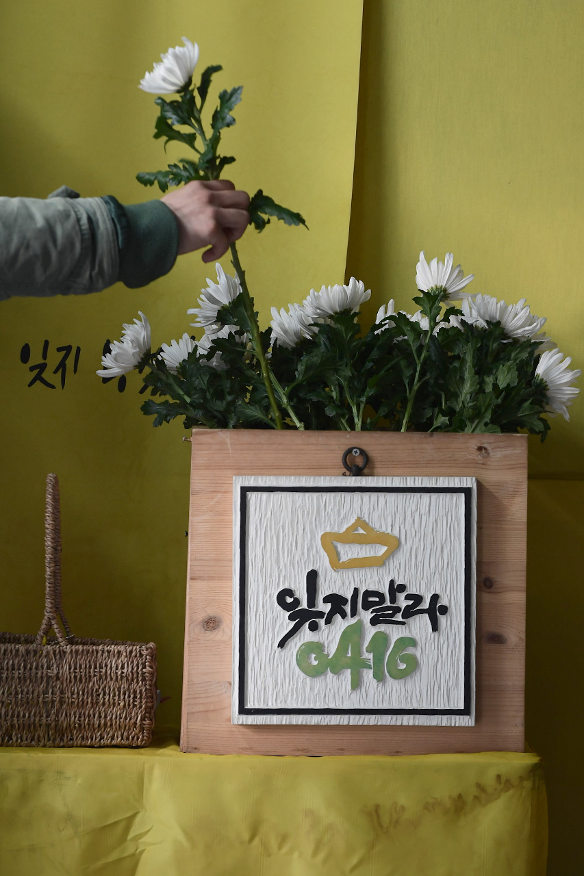 세월호 참사 1000일째를 맞이한 9일 오후 서울 종로구 광화문광장에 마련되어 있는 '세월호 참사 희생자 및 미수습자 광화문 분향소'를 찾은 시민이 희생자들의 영정사진앞에 놓아둘 하얀 국화꽃을 챙겨들고 있다.