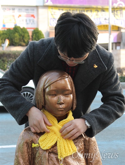 9일 오후 부산일본총영사관 앞 위안부 평화의 소녀상에 소녀상 지킴이 김성갑(24)씨가 시민이 전해준 목도리를 매어주고 있다.  
