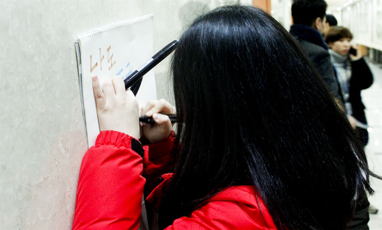 기자회견에 참석한 틴즈디모의 스텝이 국회 복도의 벽에 스케치북을 대고, 자신의 의견을 써넣고 있다.