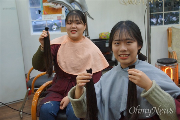 이수미(20), 이다건(18) 자매가 기부하기 위해 25cm 이상 자른 머리카락을 들어보이며 웃음을 짓고 있다.