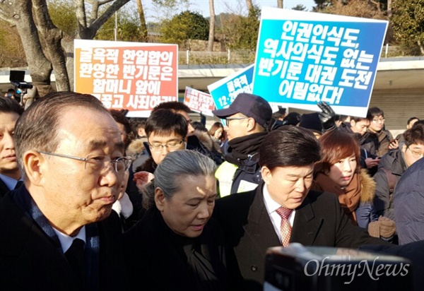 반기문 전 유엔사무총장이 17일 오전 고 노무현 전 대통령 묘소를 참배하기 위해 차량에서 내려 이동하자 시민이 항의하는 내용의 손팻말을 들고 서 있다.