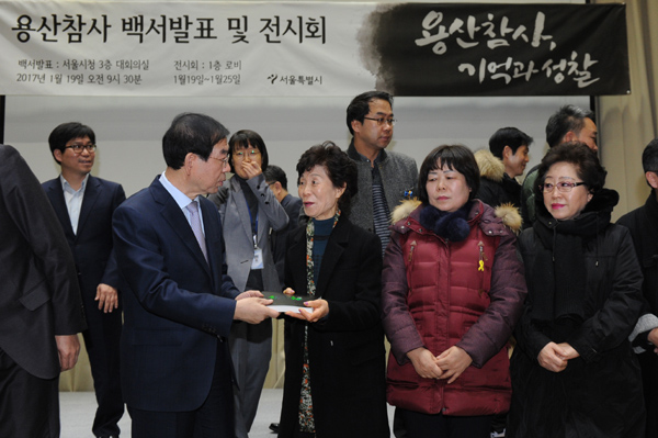박원순 서울시장이 19일 오전 시청 대회의실에서 용산참사 유가족들에게 용산참사 백서를 전달하고 있다.