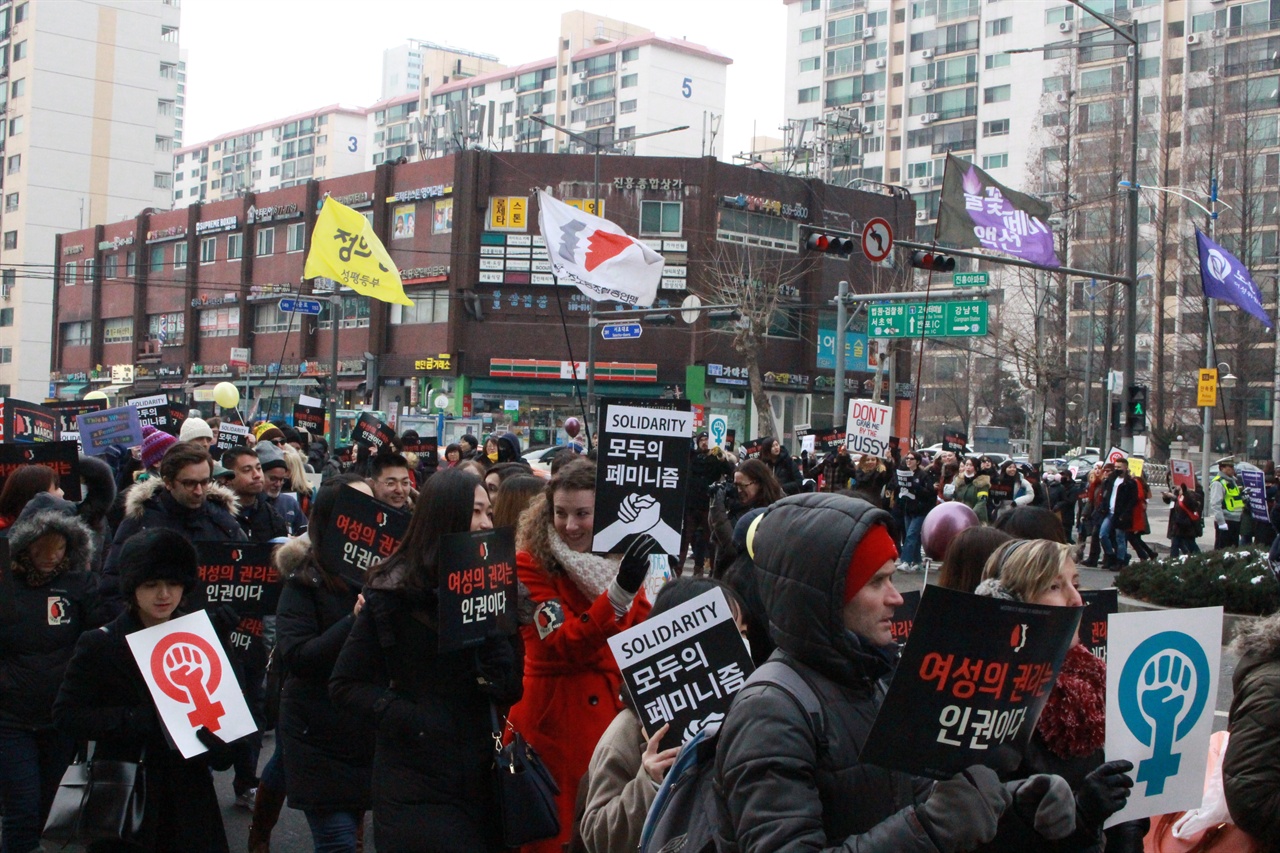  21일 '세계 여성 공동행진'에 참여한 사람들이 길을 건너고 있다. 이날 행진에 참여한 사람들은 3시 기준 약 1,000명으로 집계됐다.