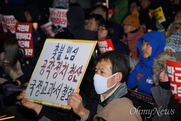 11일 오후 대구백화점 앞에서 열린 박근혜 탄핵 대구시국대회에서 한 참가자가 촛불민심이라며 국정교과서 철회를 요구하는 피켓을 들고 앉아 있다.