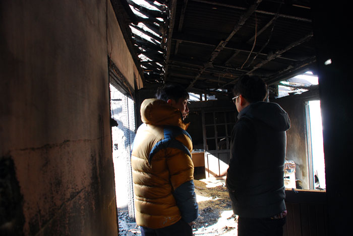 화재 소식을 듣고 찾아온 친구와 오산권씨가 불탄 집을 돌아보며 위로하고 있다. 