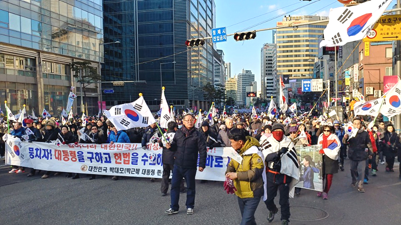 한국은행과 서울시청광장 사이를 행진하는 박사모 집회 참가자들이 태극기와 성조기를 흔들며 명동거리를 지나고 있다