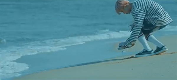  '봄날' 뮤직비디오에서 지민은 바닷가에 놓인 누군가의 신발을 집어든다.