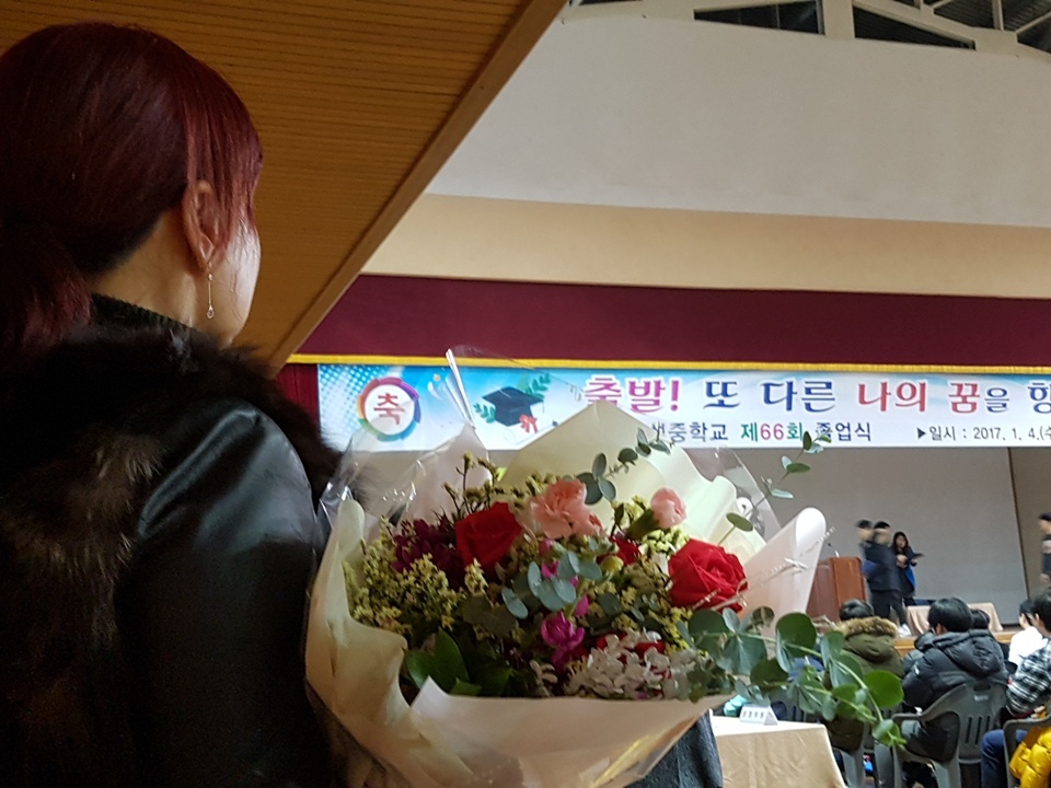 졸업식에서 아이이게 전달할 꽃다발을 들고 있는 학부모.