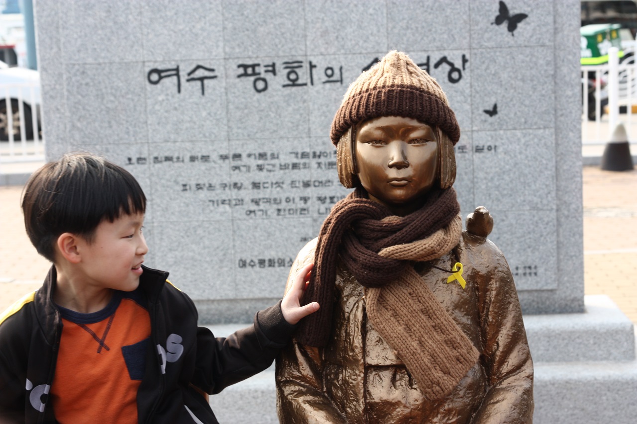 98주년 3.1절을 맞아 전남 여수 이순신 광장 앞에 세워진 평화의 소녀상에 한 어린이가 앉아있다. 