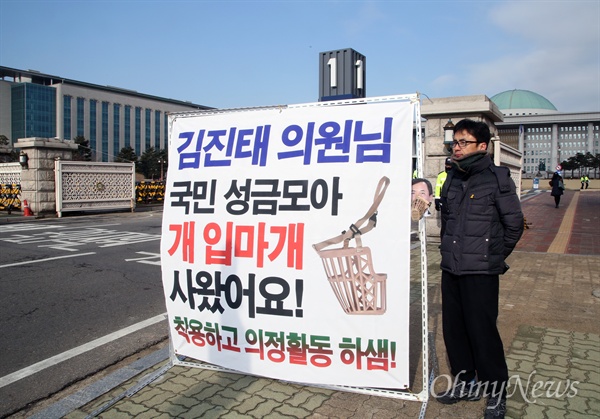 '둥글이' 박성수씨가 2일 오전 서울 여의도 국회 정문 앞에서 "김진태 의원님, 국민 성금 모아 개 입마개 사왔어요! 착용하고 의정활동 하셈!"이라고 적은 플래카드를 펼치고 일인시위를 하고 있다. 
