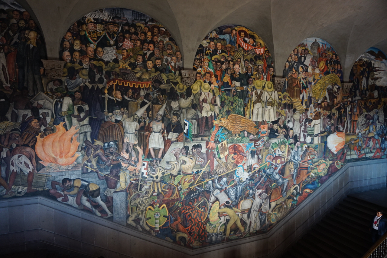 국립궁전 내부 1층에서 2층 계단 복도 사이의 벽면에 그려진 디에고 리베라의 벽화. 가운데 부분은 스페인의 침략과 식민지배의 수난, 전쟁과 독립 등을 표현하고 있습니다.