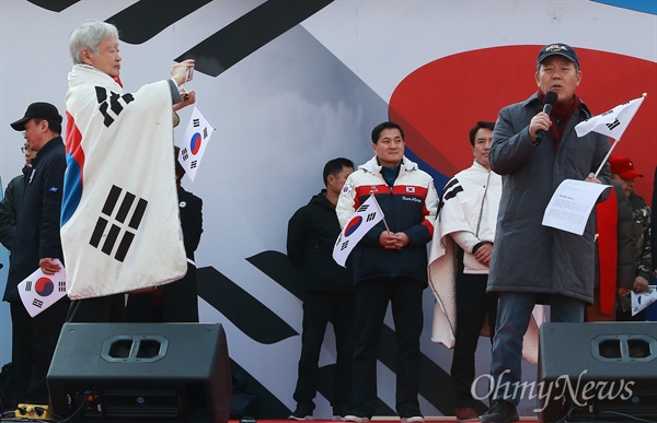 박근혜 대통령 법률대리인인 김평우 변호사가 4일 오후 서울 덕수궁 대한문앞에서 열린 '탄핵기각을 위한 국민총궐기 운동본부’(탄기국) 주최 제16차 박근혜 대통령 탄핵기각 촉구 집회에서 발언하고 있다. 김 변호사와 함께 대통령 법률대리인인 서석구 변호사가 김 변호사의 발언을 스마트폰으로 촬영하고 있다.