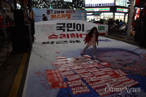 4일 오후 대구 중앙로에서 열린 박근혜 퇴진 대구시국대회에서 참가자들이 거리행진을 끝낸 후 대형 현수막을 펼쳐놓자 한 어린이가 박근혜 대통령 얼굴을 밟으며 뜀박질을 하고 있다.