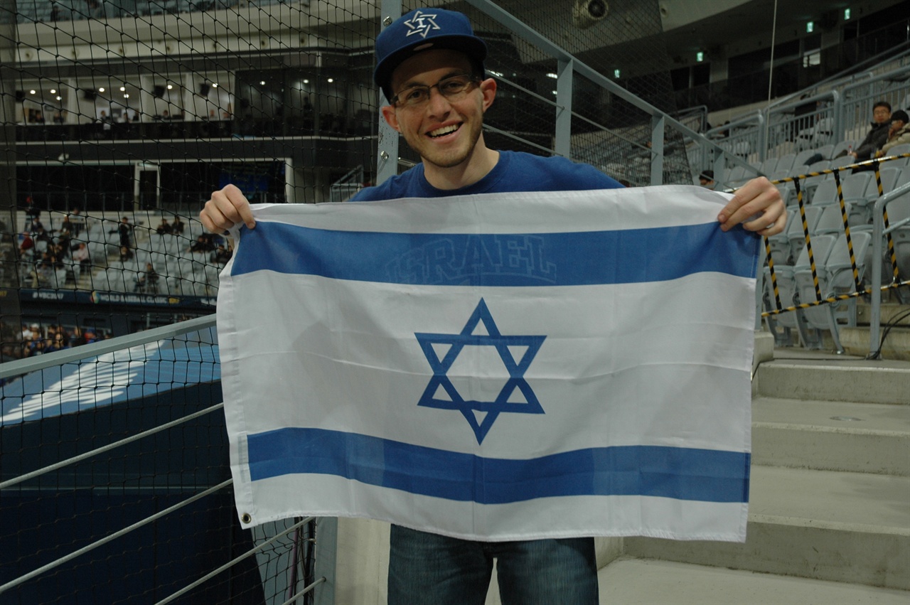 이스라엘 국기를 펼쳐 보이는 관중 이스라엘에 6년 반동안 거주한 적이 있다고 밝힌 이 청년은 야구가 더욱 세계적인 스포츠가 되었으면 한다는 소망을 밝혔다.