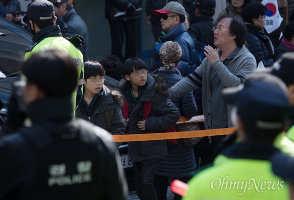  15일 오후 서울 강남구 삼성동 박근혜 전 대통령 자택 앞에서 박 전 대통령 지지자들이 태극기 등을 들고 집회를 이어가자 인근 초등하교 학생들이 경찰과 보호자의 보호를 받으며 하교하고 있다. 