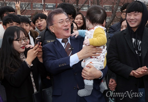  더불어민주당 대선주자로 나선 문재인 전 대표가 20일 광주 전남대를 방문해 한 지지자가 안긴 아이를 안고 있다. 