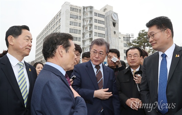 더불어민주당 대선주자로 나선 문재인 전 대표가 2017년 3월 20일 오전 광주 동구 옛 전남도청 앞 5·18민주광장에서 윤장현 광주시장의 이야기를 듣고 있다. 뒤로 보이는 건물이 5·18 민주화운동 당시 헬기사격 탄흔이 남아있는 전일빌딩이다. 