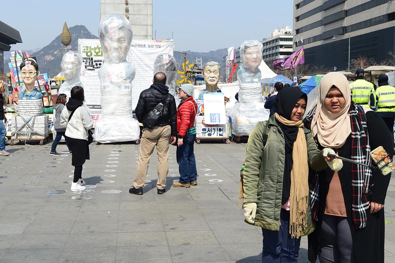 22일 오후 서울 광화문광장의 새로운 명물로 떠올라 서울 시민들은 물론 외국인 관광객들에게도 '큰사랑'을 받았던 '포승줄에 묶인 박근혜 前 대통령'의 조형물을 비롯한  '김기춘 전 청와대 비서실장', '조윤선 전 문화체육부 장관' 등의 조형물들이 다른곳으로 옮겨지기 위해 포장작업이 진행중인 가운데 외국인 관광객들이 조형물을 배경으로 사진을 찍고 있다.