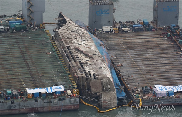 24일 오후 전남 진도군 동거차도 앞바다에서 수면위 13m까지 올라온 세월호가 2척의 잭킹바지선에 와이어로 묶여 반잠수식 선박으로 이동을 기다리고 있다. 해양수산부는 이날 오후 4시께 3㎞ 떨어진 곳에서 대기 중인 반잠수식 선박으로 본격 이동한다고 밝혔다.