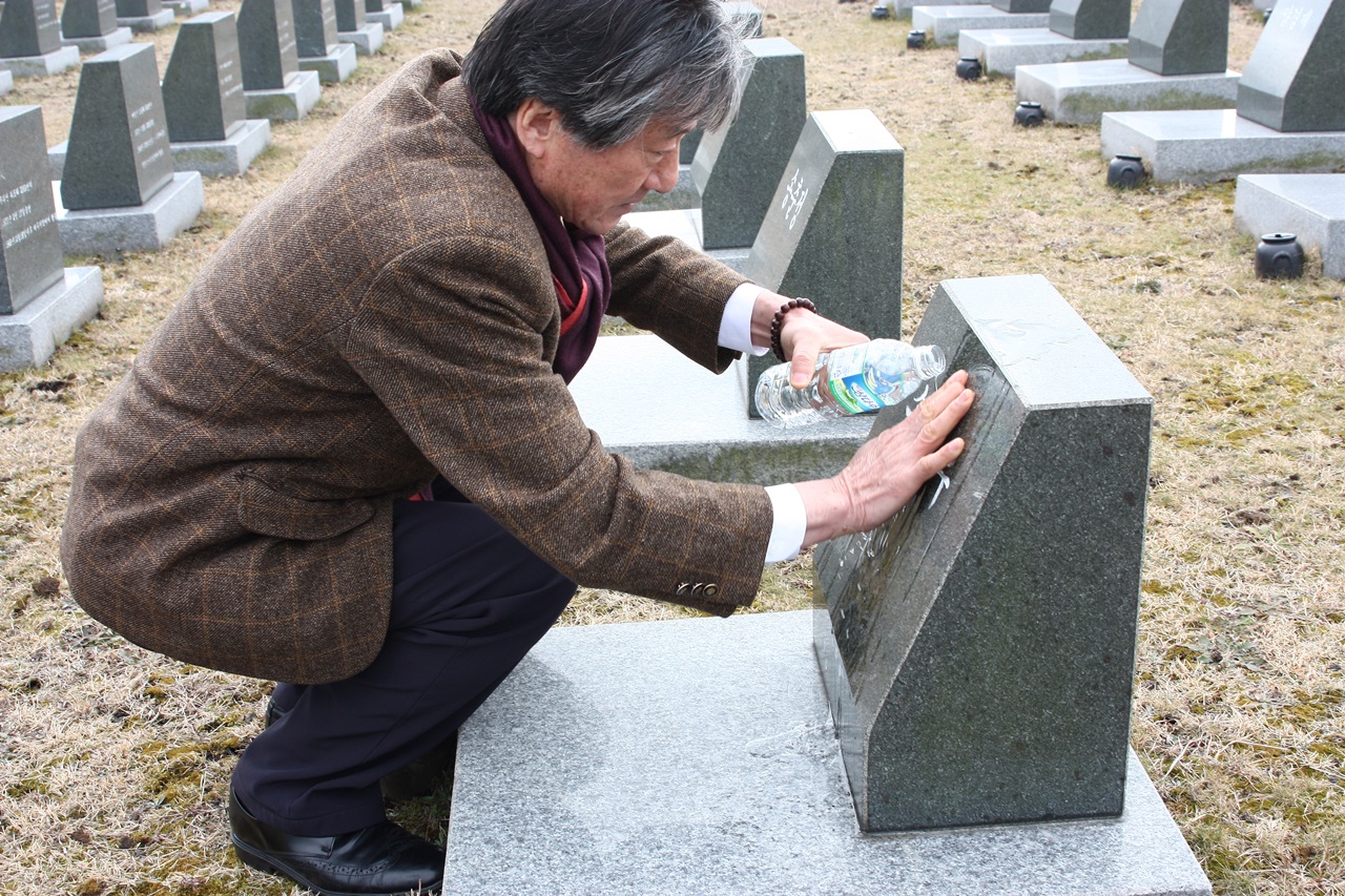  추모후 물대신 술을 뿌리고 있는 송승문 전 사무처장의 모습