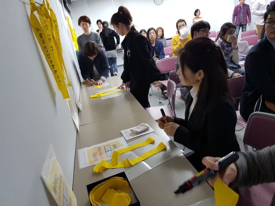 참가자들이 헌화 뒤 희생자들에게 보내는 메세지를 노란 리본에 쓰고 있다