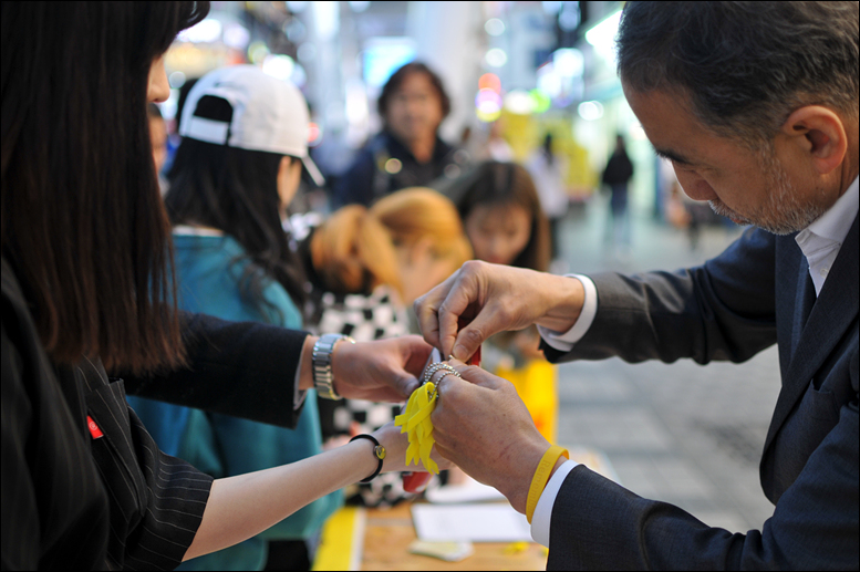 ‘님들의 행진’ 서준수 회원이 한 시민의 지갑에 노란리본을 달아주고 있다.