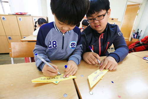 13일 인천 동수초교 1?6학년 학생이 함께 노란색 종이배를 만들고 추모의 글을 쓰고 있다.