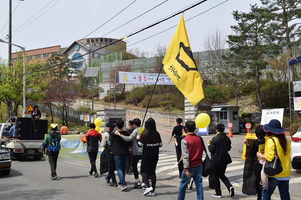  16일 오후 세월호 참사 3주년을 맞아 안산 중앙역에서 출발한 ‘봄길 행진’에 참석한 시민들이 세월호 배 모양의 노란깃발을 앞세우고 단원고 정문을 지나가고 있다. 