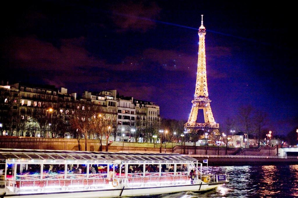 프랑스 파리를 상징하는 건축물 에펠탑. 화려한 야간 조명이 켜졌다. 아래 센강 유람선이 보인다.