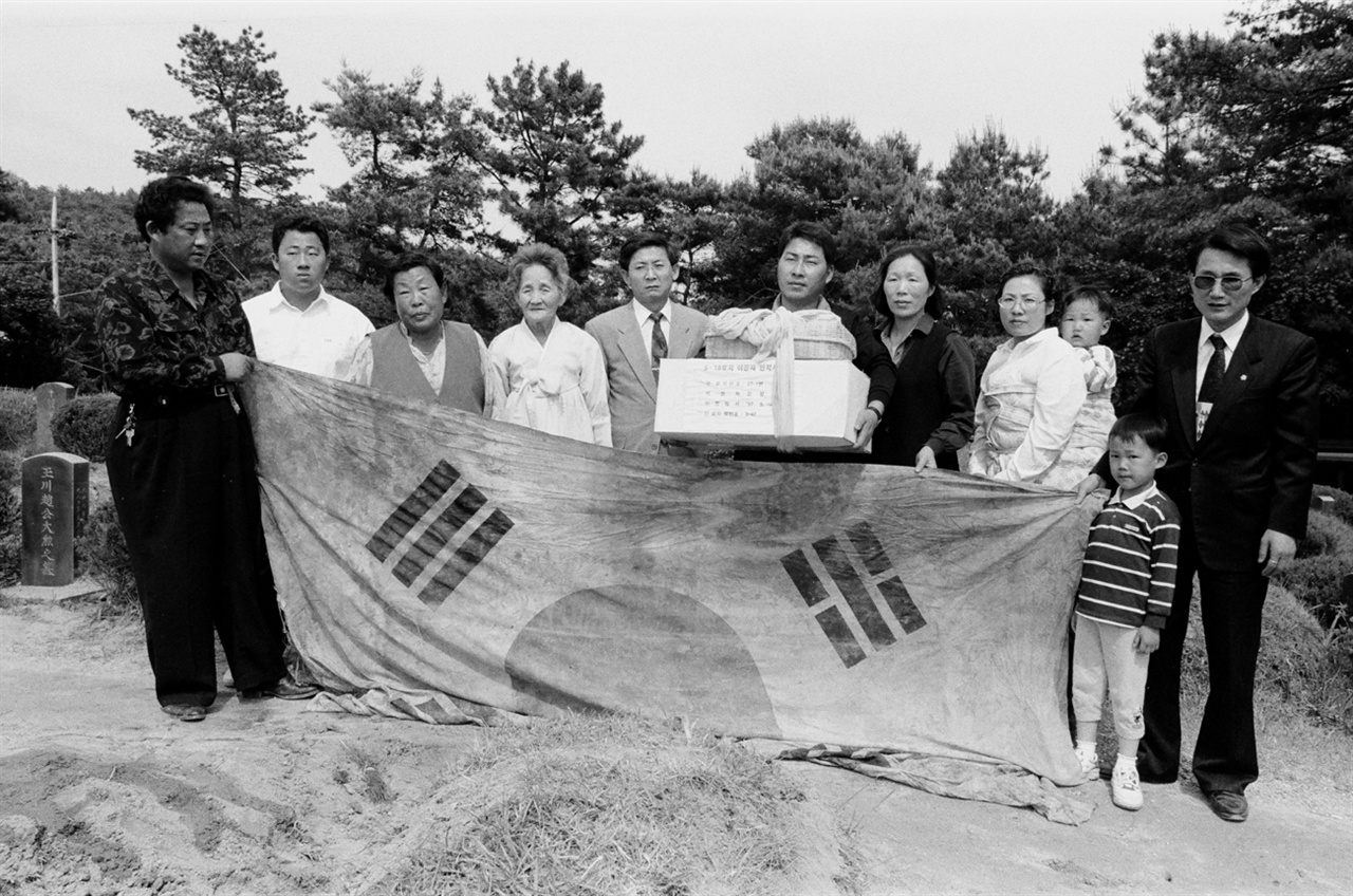 망월동 구묘역에서 유골을 수습한 후 관에서 나온 태극기를 펼쳐들고 기념사진을 찍는 고 김형영씨 가족(1997.05)